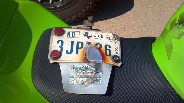 License plate after dislodged from between tire and swing arm.